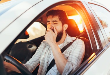 Ein Mann gähnt im Auto.